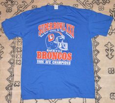 a blue super bowl xx t - shirt laying on top of a rug