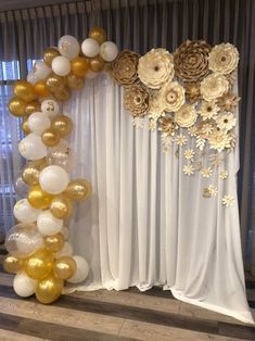 gold and white balloons are hanging on the wall next to a drapes with flowers