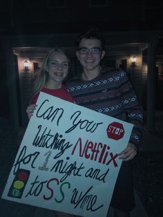 a man and woman holding a sign in front of a house