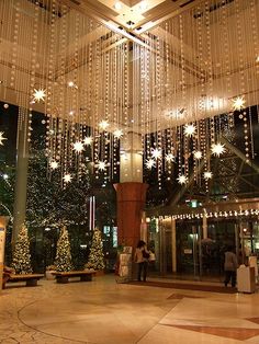 the inside of a building decorated with lights and christmas tree decorations in front of it