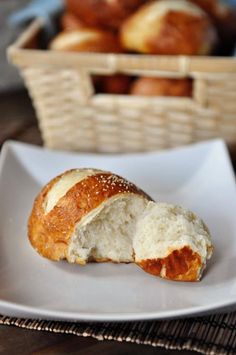 a piece of bread sitting on top of a white plate next to a basket filled with pastries