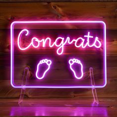 a neon sign that says congrats with two feet on it and the words