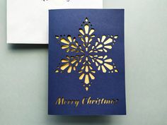 a blue christmas card with gold foil snowflake on it and a white envelope