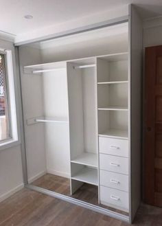 an empty closet with white shelves and drawers