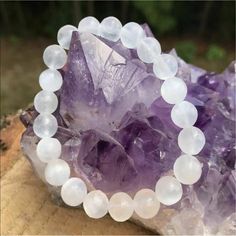 an amethorate and white beaded bracelet sitting on top of a rock