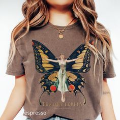 PRODUCTON TIME: 1-3 Days  SHIPPING TIME: 2-5 Days (International 10-30 Days) This stunning Comfort Colors® butterfly shirt features a vintage Art Nouveau illustration by F.X. Leyendecker, capturing the delicate beauty of a fairy with intricate butterfly wings. Perfect for adding a touch of elegance and whimsy to any wardrobe, this artistic graphic tee blends nature-inspired charm with retro fantasy style. It's an ideal gift for fairy core, cottage core, and art lovers, as well as anyone who appr Spring Fairycore Graphic Print T-shirt, Fairycore Graphic Print Cotton T-shirt, Fairycore Graphic Print Short Sleeve T-shirt, Fairycore Cotton T-shirt With Graphic Print, Summer Fairycore Top With Graphic Print, Green Fairy Grunge Tops For Spring, Whimsical Cotton Short Sleeve Tops, Cotton Fairycore T-shirt For Summer, Summer Fairycore Cotton T-shirt