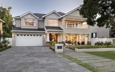 a large house with two garages in front of it and landscaping around the driveway