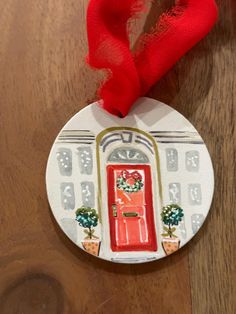 a christmas ornament with a red ribbon hanging from it's side on a wooden table