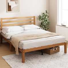 a bed with white sheets and pillows in a room next to a potted plant