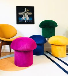 brightly colored stools and footstools are arranged in a room with white walls