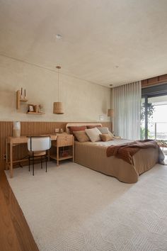 a bedroom with a bed, desk and window overlooking the water in front of it