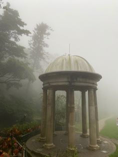 a gazebo in the middle of a park on a foggy day