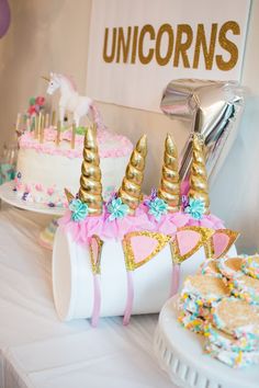 a table topped with cakes covered in unicorn themed icing and other desserts on top of it