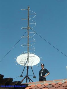 a man standing on top of a roof next to a satellite dish