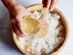 someone is pouring oil on rice in a wooden bowl