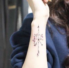 a woman's wrist with an arrow tattoo on it