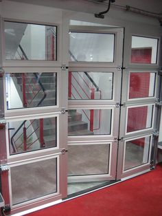 an open glass door with red carpeting and stairs in the background, on top of a staircase