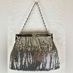 a silver purse hanging on a wall with chains attached to the front and side of it