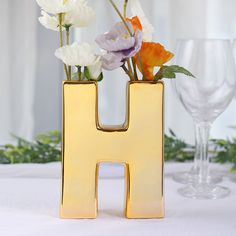 a gold letter shaped vase with flowers in it