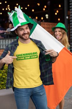 a man in a green shirt and hat holding an irish flag while standing next to a woman