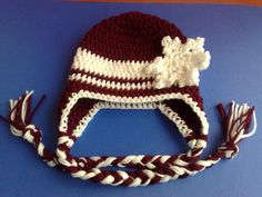 a crocheted hat with a white and maroon sheep on it sitting on top of a blue surface