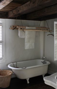 an old fashioned bathtub in a bathroom with white walls and wood beams on the ceiling