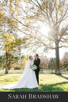 a bride and groom standing in front of a tree with the sun shining down on them