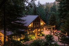 a large wooden building surrounded by trees at night with lights on it's roof