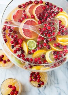 a glass bowl filled with oranges and cranberries