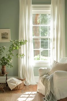 a living room filled with furniture and a window covered in white curtained drapes