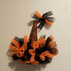 an orange and black mesh wreath hanging on the wall next to a toilet paper roll