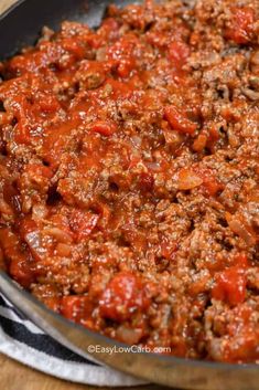 a pan filled with meat and sauce on top of a wooden table