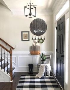 an entry way with black and white checkered rugs on the floor, chandelier hanging from the ceiling