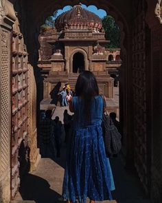 a woman in a blue dress is walking through an archway