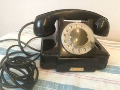 an old black telephone sitting on top of a bed