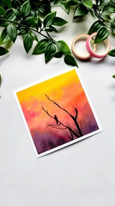 a card with an image of a bird on a tree branch and two rings next to it