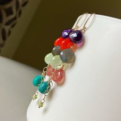 New gemstone mix!   From the top: purple Amethyst,  Carnelian, Labradorite, pale green Prehnite, Strawberry quartz, Chrysocolla, Peridot. These dreamy gems are all suspended from 14k yellow goldfilled links and earwires.   Gems measure approximately 8-10mm wide. Total earring length is 2 + 11/16 inches. Please note that pictures of my jewelry are enlarged. The gemstone colors may vary on the device being used to view items. I do not alter the gemstone colors in my photos, but the backdrop can alter their look. My practice is always to add my jewelry last before heading out and to remove my jewelry first after returning home. Here are a few other jewelry care tips: Avoid direct contact with perfume, hairspray or other chemicals. Remove jewelry when bathing, showering or swimming. Remove jew Purple Multi-stone Bohemian Jewelry, Purple Bohemian Multi-stone Jewelry, Purple Bohemian Everyday Jewelry, Bohemian Multicolor Amethyst Gemstones, Bohemian Briolette Gemstone Earrings, Bohemian Multi-stone Dangle Earrings, Natural Briolette Gemstones In Bohemian Style, Bohemian Briolette Gemstones, Multicolor Teardrop Natural Stones Gemstones