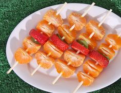 oranges and strawberries are arranged on skewers on a white platter