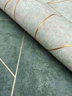 a green rug with gold lines on the floor next to a white and black wall