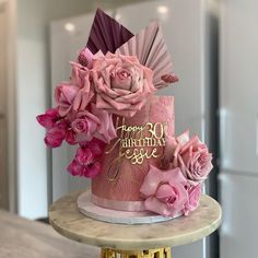 a pink birthday cake decorated with flowers on a table