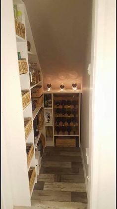 an open pantry with shelves filled with food and baskets on the bottom shelf, next to a door that leads to another room