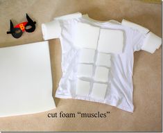 a white t - shirt with cut foam muscles on it next to scissors and glue