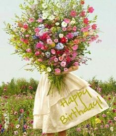 a woman holding a bouquet of flowers with the words happy birthday written on it