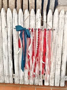 a white picket fence with red, white and blue ribbons hanging on it