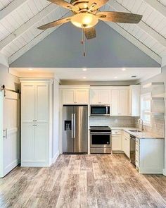 an empty kitchen with a ceiling fan and white cabinets