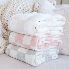 towels stacked on top of each other in front of a pile of knitted blankets