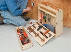 a man sitting on the floor with tools in front of him and his workbench