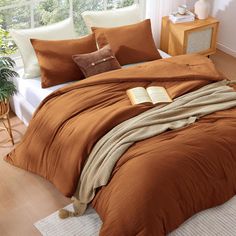 a bed with an orange comforter and pillows on top of it in a room