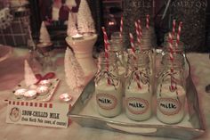 there are many bottles with candy canes in them on the table next to candles