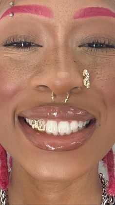 a close up of a woman with piercings on her nose and eyebrows smiling at the camera